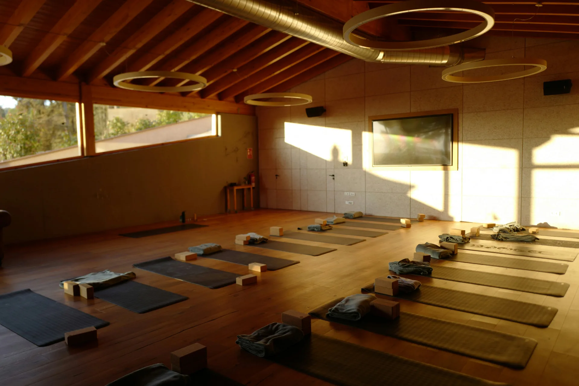 Heller Yoga-Raum mit Matten, Kissen und Blocks im warmen Abendlicht